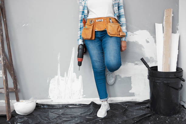 Cropped shot of a young woman doing DIY leaning against wall being renovated Cropped shot of a young woman doing DIY leaning against wall being renovated. High quality photo woman wearing tool belt stock pictures, royalty-free photos & images