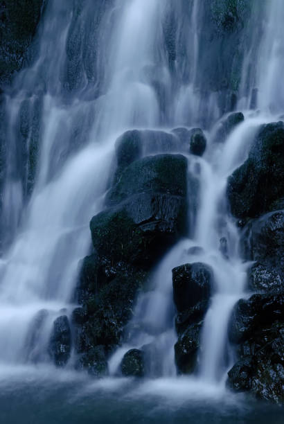 istock Beautiful mountain rainforest waterfall with fast flowing water and rocks, long exposure. Natural seasonal travel outdoor background with sun shining. Stream waterfall on rocks in the forest 1459959921