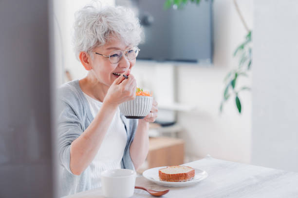 Senior woman eating breakfast with a smile stock photo