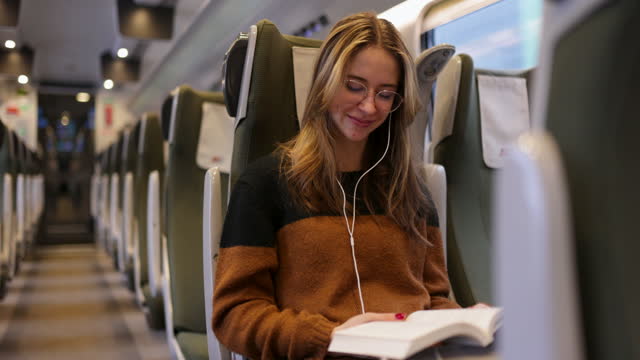 Teenage girl travelling on modern train and reading a book