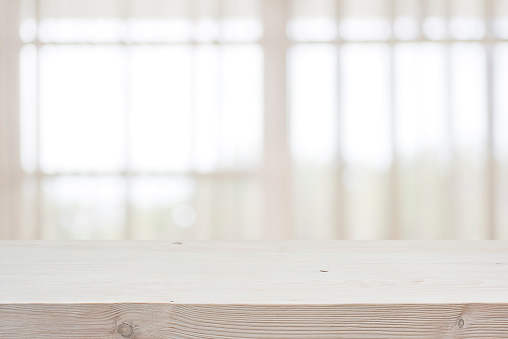 Empty wooden table top on blur curtained window background