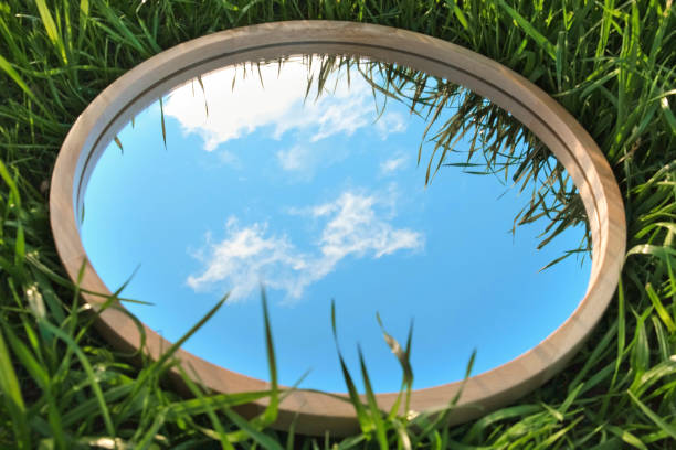 istock Cloudy Blue Sky Reflection in Round Wood Mirror on Summer Field with Green Grass. Nature Concept. Earth Day. Save Environment. Peace. Ecology Protection. Climate Change, Global Warming Effect Problem 1459965711