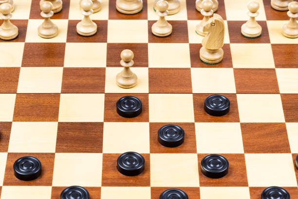 istock beginning of chess - checkers game on wood board 1459966632