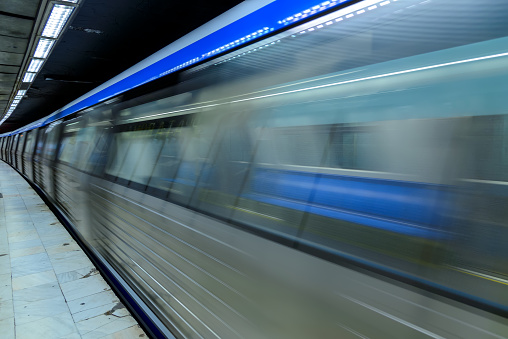 Blurred motion of the train in underground station of subway. Long exposure of an underground train in a train station. Urban scene, city life, public transport and traffic concept