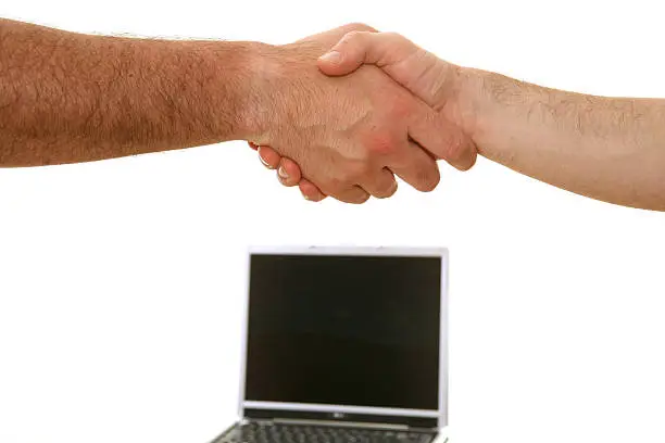 Business handshake with a laptop in the background
