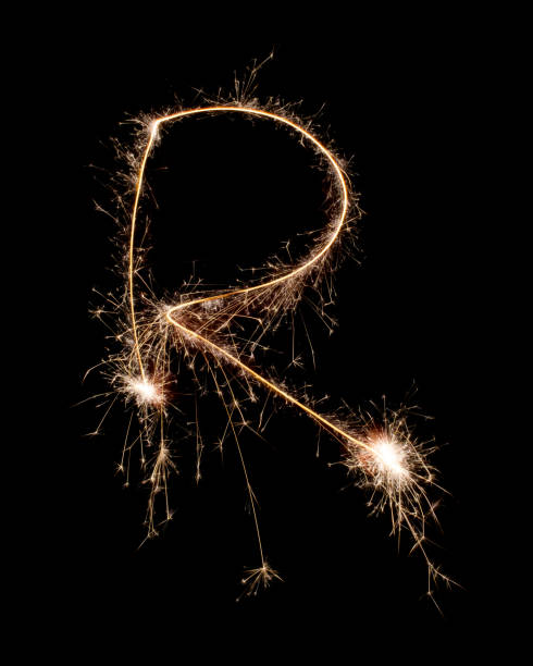 istock Sparkling burning creative letter R isolated on black background. Beautiful glowing golden overlay object for design holiday greeting card. Creative lettering R written with burning sparklers 1459968391