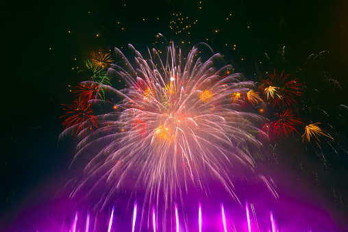 Beautiful colorful fireworks display lights up the sky with dazzling display during New Year celebration. Abstract colored fireworks background with copy space. Celebration and anniversary concept
