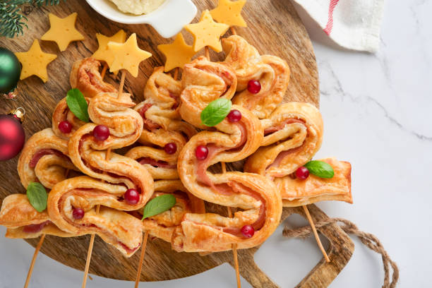 istock Christmas or New Year appetizer. Christmas tree shape puff pastry buns with cheese and ham. Group of Christmas tree shapes on wooden board. Festive idea for Christmas or New Year dinner. Top view. 1459971425
