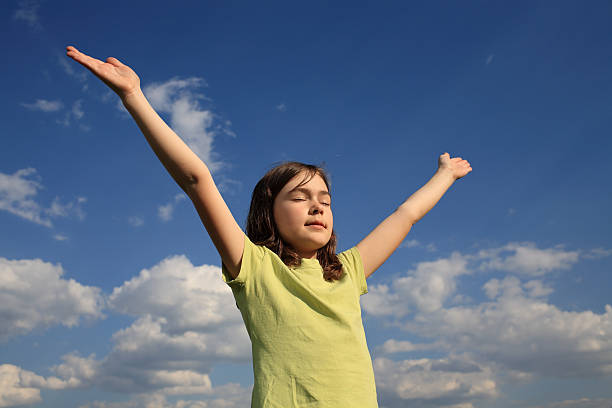 istock Girl holding hands up against blue sky 145997239