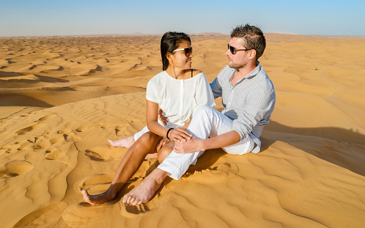 Couple on a Safari trip to the Sand dunes of Dubai United Arab Emirates, sand desert on a sunny day in Dubai.