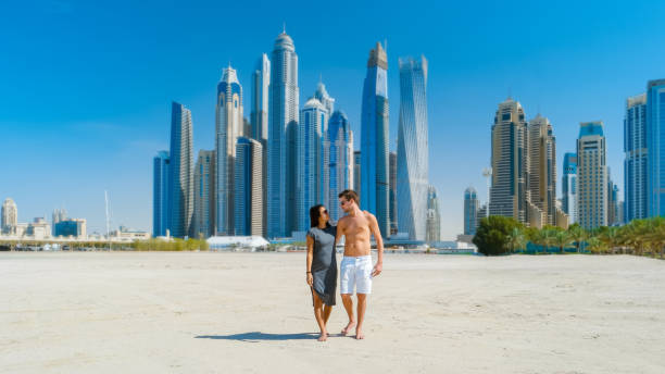 paar auf einer städtereise nach dubai zu fuß am strand von jumeirah beach dubai vereinigte arabische emirate - dubai beach hotel skyline stock-fotos und bilder