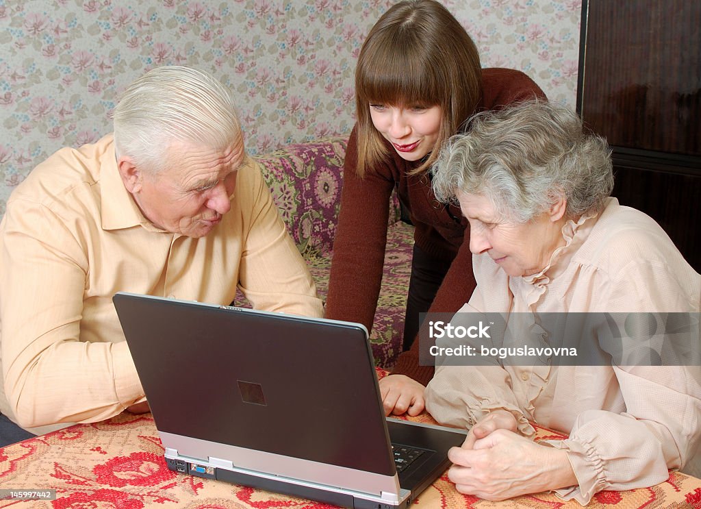 Abuelos y granddaughter mirando a la computadora portátil - Foto de stock de 20 a 29 años libre de derechos