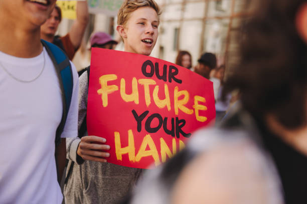 istock Teenage boy holding a banner during a climate change protest 1459976812