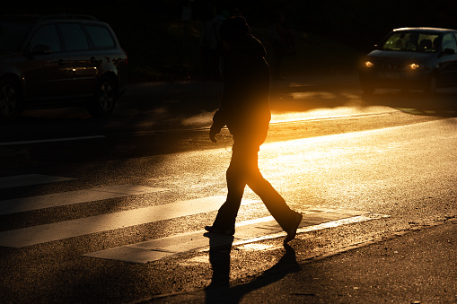 Person crossing street in sunset city traffic