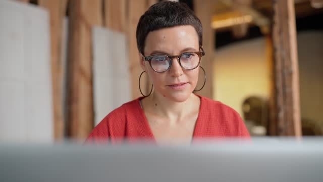 Positive brunette woman architect in eyeglasses working on laptop