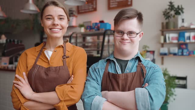 Happy male waiter with Down syndrome standing with a girl colleague