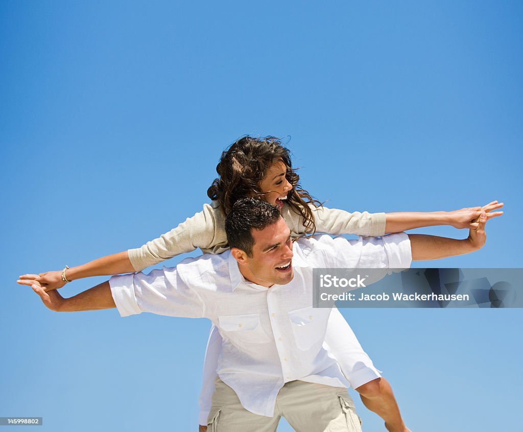 Rir jovem dando Cavalitas para mulher contra o céu azul - Royalty-free Adulto Foto de stock