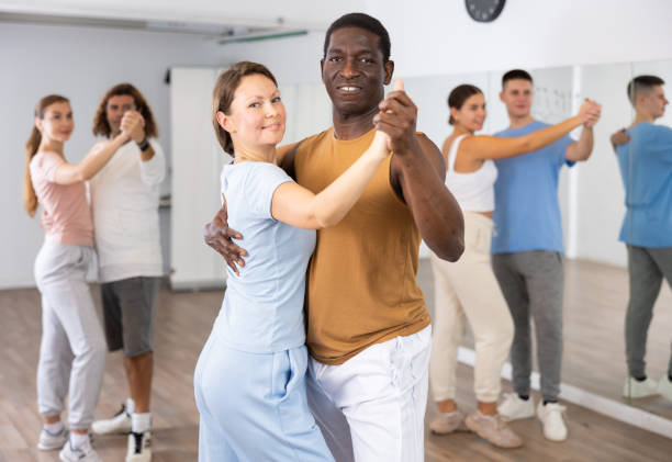 istock Smiling multiracial men and women enjoying partner dance while training together in modern studio 1459990924