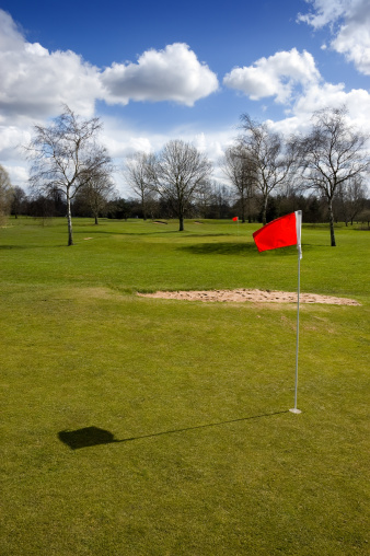 Red flag on the putting green of a golf course on a sunny winter day