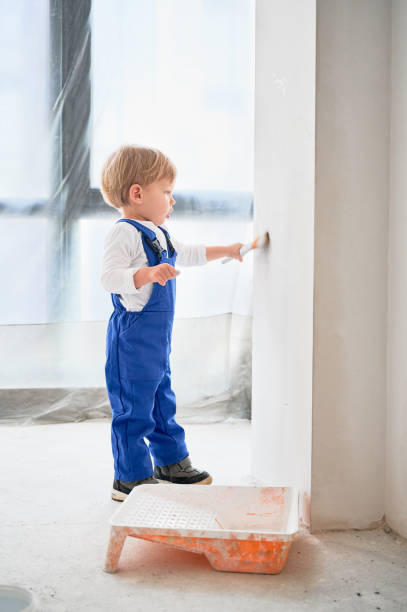 istock Little boy painting wall in apartment under renovation. 1459995801