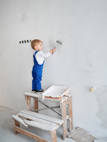 Cheerful little children having fun painting flowers on the wall.