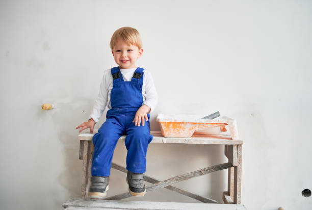 istock Happy child sitting on table in apartment under renovation. 1459995868