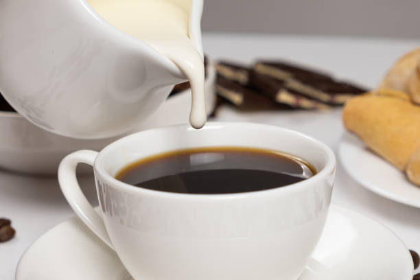 istock Cream from the milk jug is poured into coffee, making coffee with cream, cappuccino. 1459996258