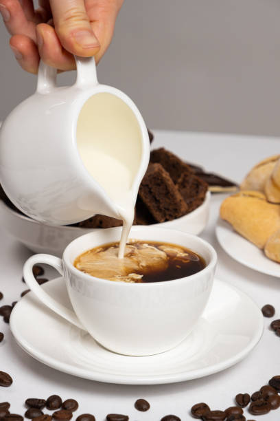 istock Cream from the milk jug is poured into coffee, making coffee with cream, cappuccino. 1459996308