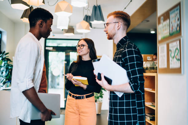 istock Smiling female speaking with colleagues in corridor 1459998522