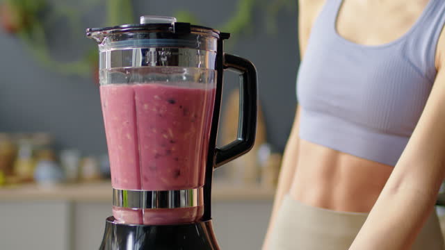 Fit Woman Making Smoothie in Kitchen Blender