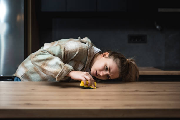 istock Young woman suffers from depression after a breakup or divorce and from obsessive compulsive disorder OCD cleans kitchen cook top to calm her nerves. Serious stressed female rubbing the home 1460000834