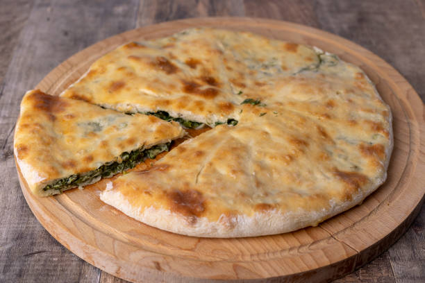 istock Pie with spinach, herbs and Suluguni cheese on a wooden board. A whole pie with a piece cut off. Traditional round flat cake with nachi 1460002400