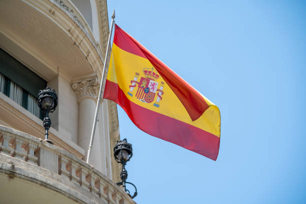 flag of spain with red and yellow colors waving in the wind during a sunny day with blue sky - spain flag built structure cloud imagens e fotografias de stock