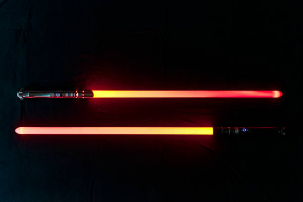 istock Two parallel red glowing laser sword blades against black background lying on the floor of living room. 1460003636