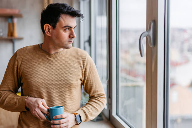 istock Young Man Drinking Coffee By The Window At Home 1460004064