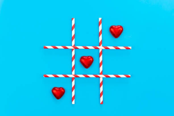 istock Heart shaped chocolates on blue background, tic-tac-toe game, flat lay. 1460005658