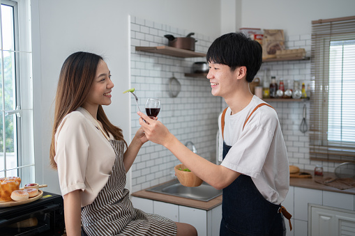 Young adorable Asian partner celebrate togehter in kitchen.