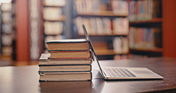 istock Library background, books on table and laptop for research, study and learning in university, school or college. Reading, bookshelf and philosophy for language, education or knowledge with pc on desk 1460007433