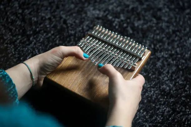 Unrecognizable Caucasian teenager girl playing a thumb piano. Kalimba or a thumb piano is a modern version of a traditional african instrument mbira.