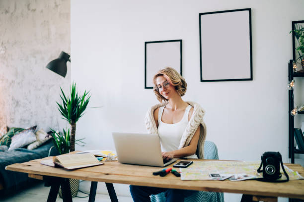 istock Young smiling woman sitting at comfortable work place and reading news on network using high speed home internet on modern laptop computer, conceptual of convenience remote work on freelance 1460008380