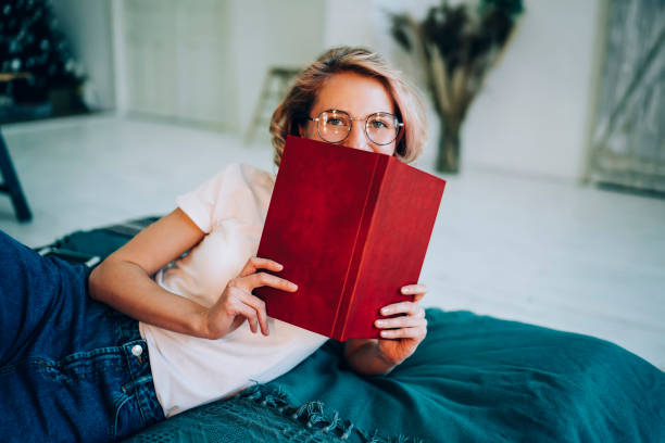 istock Relaxed modern woman covering face with book 1460009064
