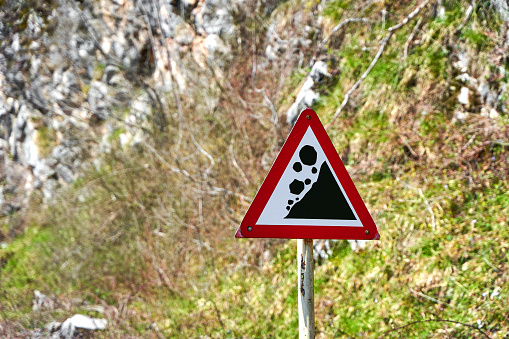 A sign warning of rock falls along a highway in the mountains.