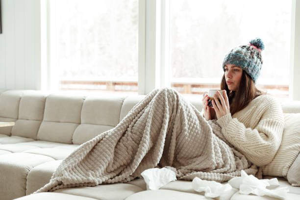 istock Beautiful woman drinking hot tea wrapped in blanket 1460009526