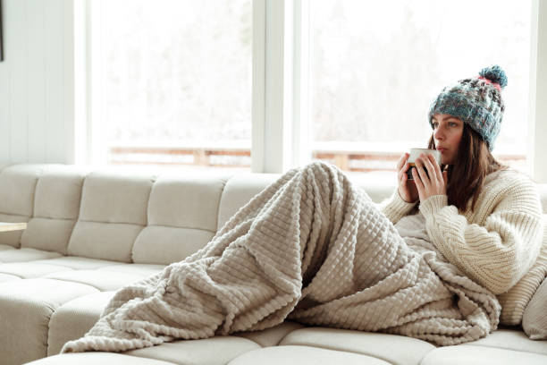 Beautiful woman drinking hot tea wrapped in blanket