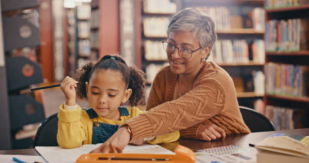istock Book, helping and senior with child learning, teaching and language homework, education and library. Creative development, kindergarten and writing support of people, grandmother or teacher with kid 1460009938