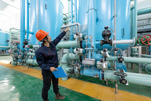 An Asian female engineer records equipment in a chemical plant