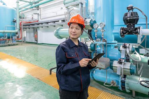 A Chinese female technician uses a tablet computer to check the equipment in a chemical plant