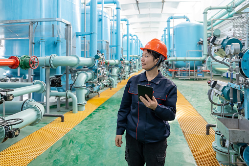 A female engineer works with a tablet computer in a chemical plant