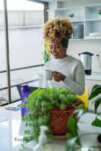istock afro latina women are inside the office where they work with their computer working and a cup of coffee in their hand 1460010298