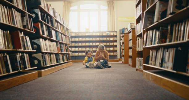 Books, reading and child with grandmother on library floor for knowledge, learning and bonding. Bookshelf, family and girl in bookstore for literature, fairytale story and educational development